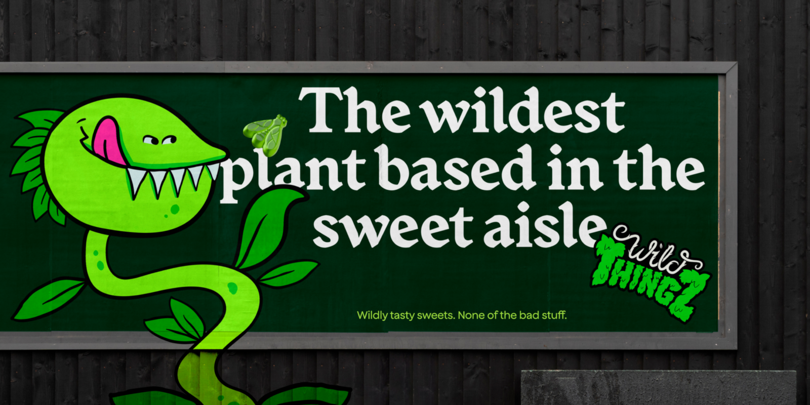 Billboard showing a cartoon green plant with teeth, captioned "The wildest plant based in the sweet aisle." Logo says "Wild Thingz." Fun, playful tone.
